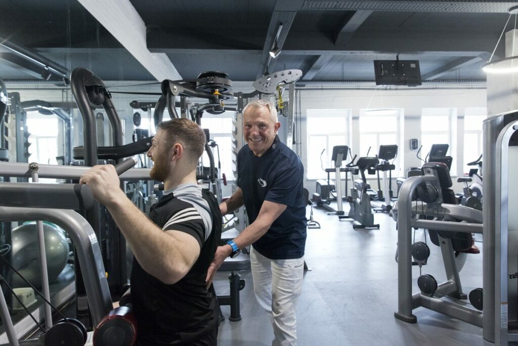 Physiotherapeut leitet einen Patienten an einem Trainingsgerät an