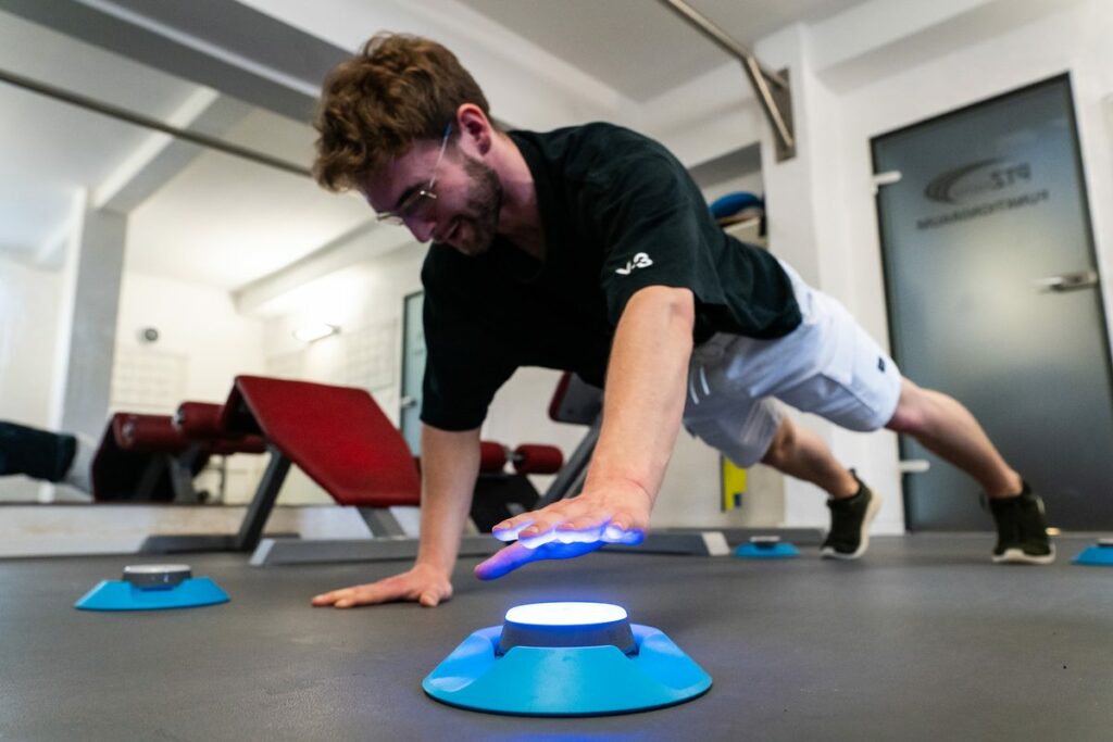 Therapeut demonstriert eine Übung beim Reaktionstraining mit Licht-Pods