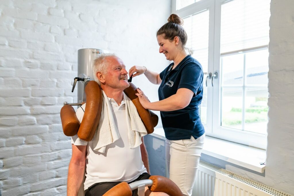 Physiotherapeutin betreut einen Patienten an einem medizinischen Trainingsgerät